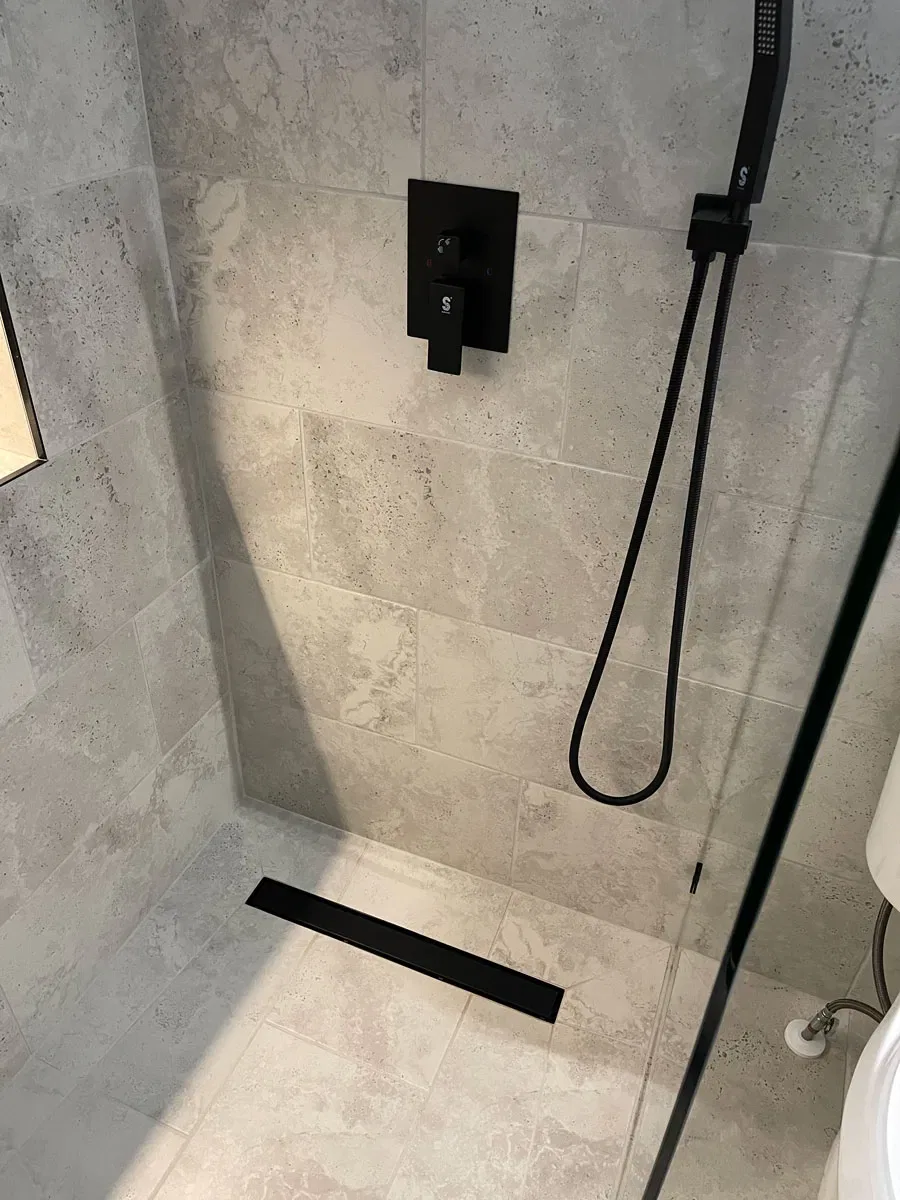 Modern shower with stone tiles and black fixtures